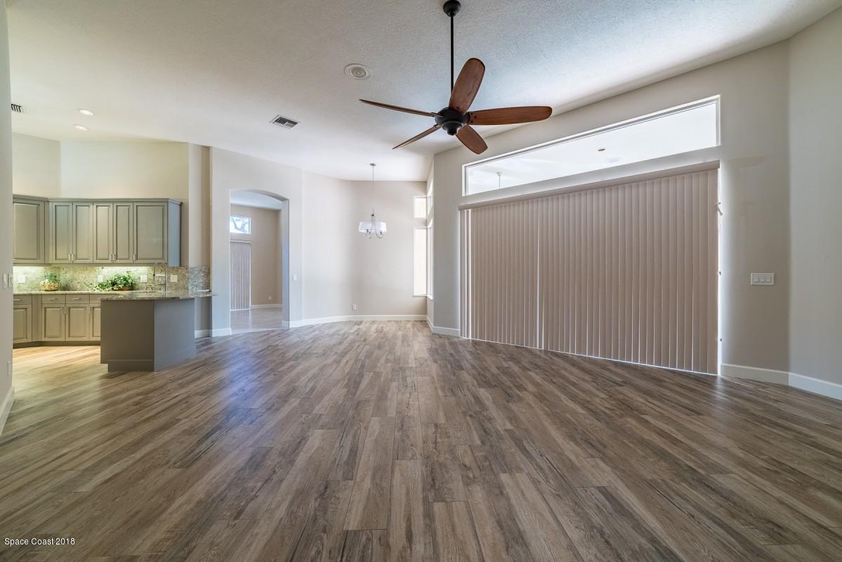 1725 Canterbury Drive Indialantic, FL 32903 - Photo 14 of 22 a view of a big room with wooden floor a ceiling fan and staircase