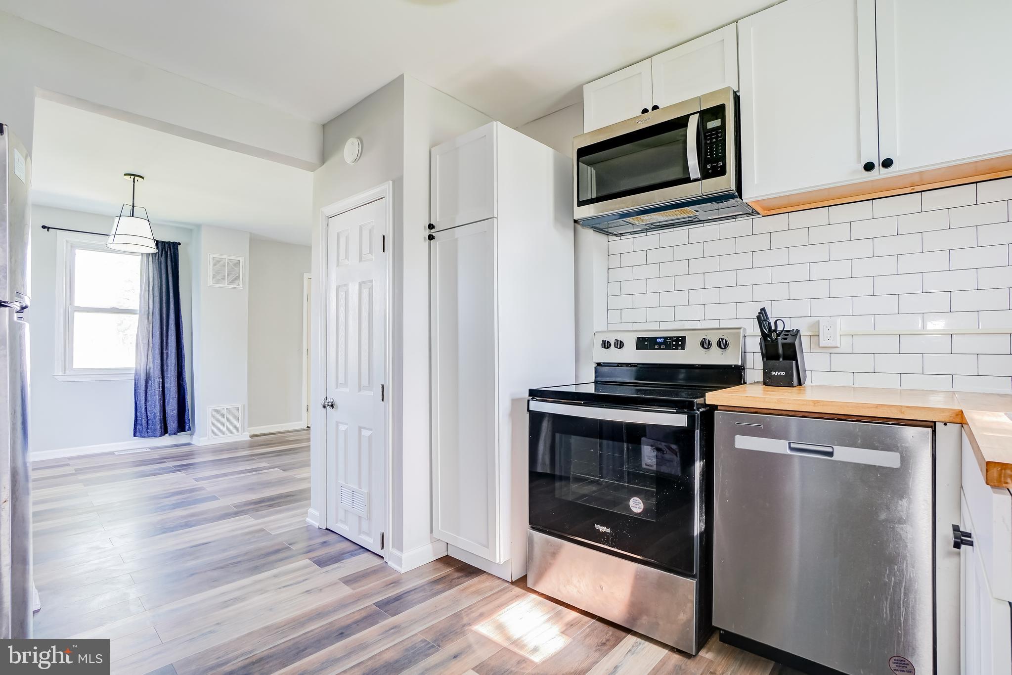 8 Avenal Road Essex, MD 21221 - Photo 9 of 17 a kitchen with stainless steel appliances granite countertop a stove a microwave and a white cabinets