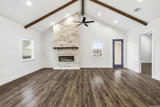 a view of an empty room with a window and wooden floor