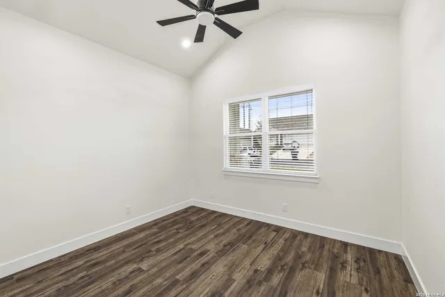 an empty room with wooden floor ceiling fan and windows