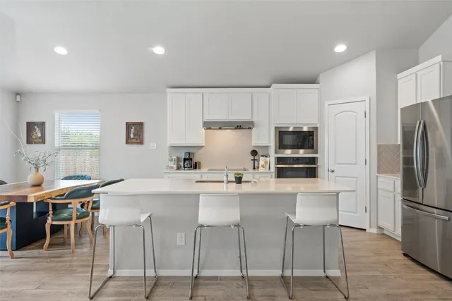 a kitchen with stainless steel appliances a table chairs refrigerator and cabinets