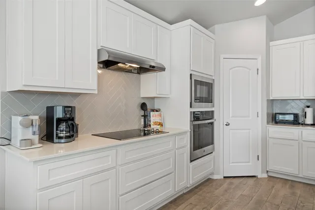 a kitchen with white cabinets and stainless steel appliances