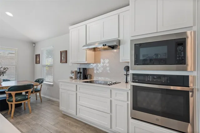 a kitchen with granite countertop white cabinets and white appliances