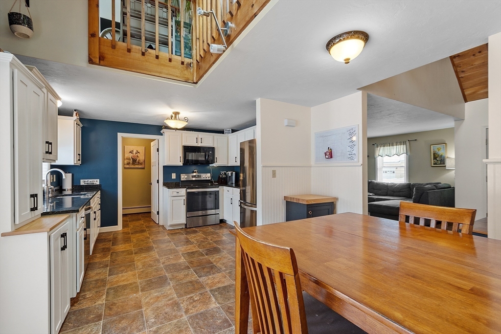 64 Peabody Road, Unit A Shirley, MA 01464 - Photo 6 of 29 a kitchen with stainless steel appliances kitchen island granite countertop a refrigerator a stove a sink dishwasher and white cabinets with wooden floor