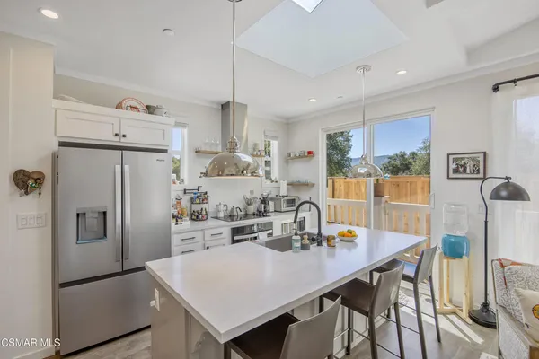 a kitchen with stainless steel appliances a dining table chairs and refrigerator