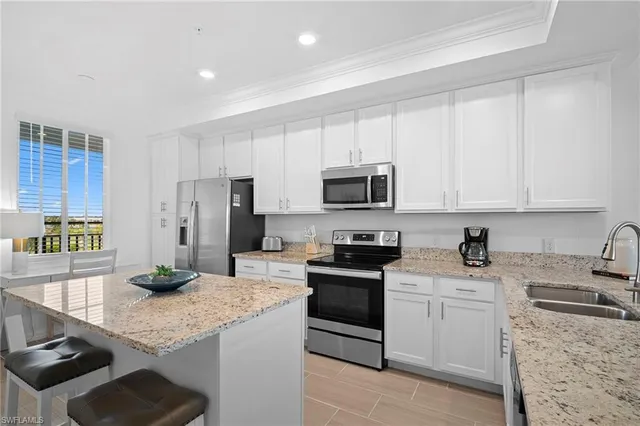 a kitchen with granite countertop a sink stainless steel appliances and white cabinets