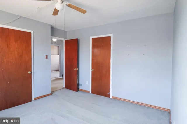 an empty room with closet and a ceiling fan