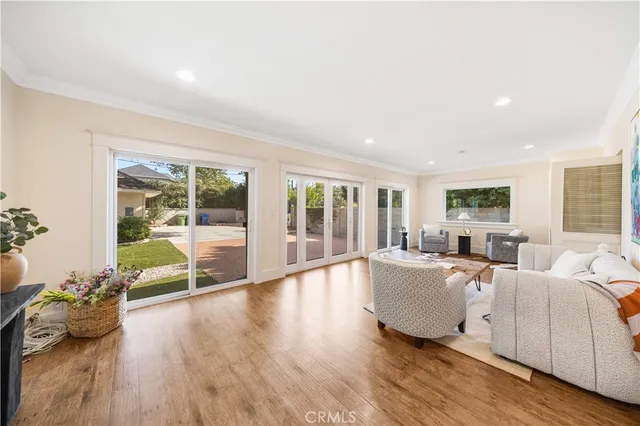 a living room with furniture large windows and wooden floor