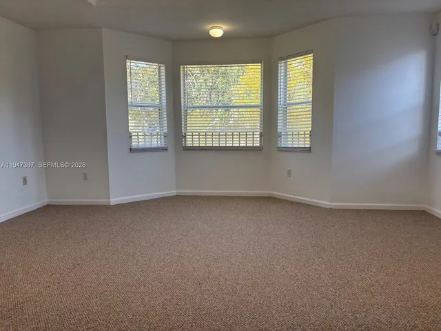 an empty room with chandelier fan and windows