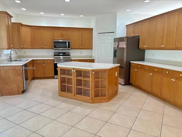 a living room with stainless steel appliances kitchen island granite countertop a sink and cabinets