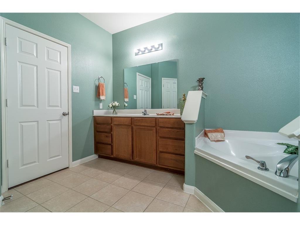 1009 Hawthorne Road Anna, TX 75409 - Photo 17 of 22 Bathroom featuring a built-in corner tub, a double vanity with wood-finish cabinetry, and a framed mirror with overhead lighting