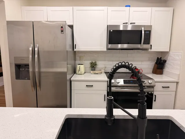 a kitchen with stainless steel appliances white cabinets and a wooden floor