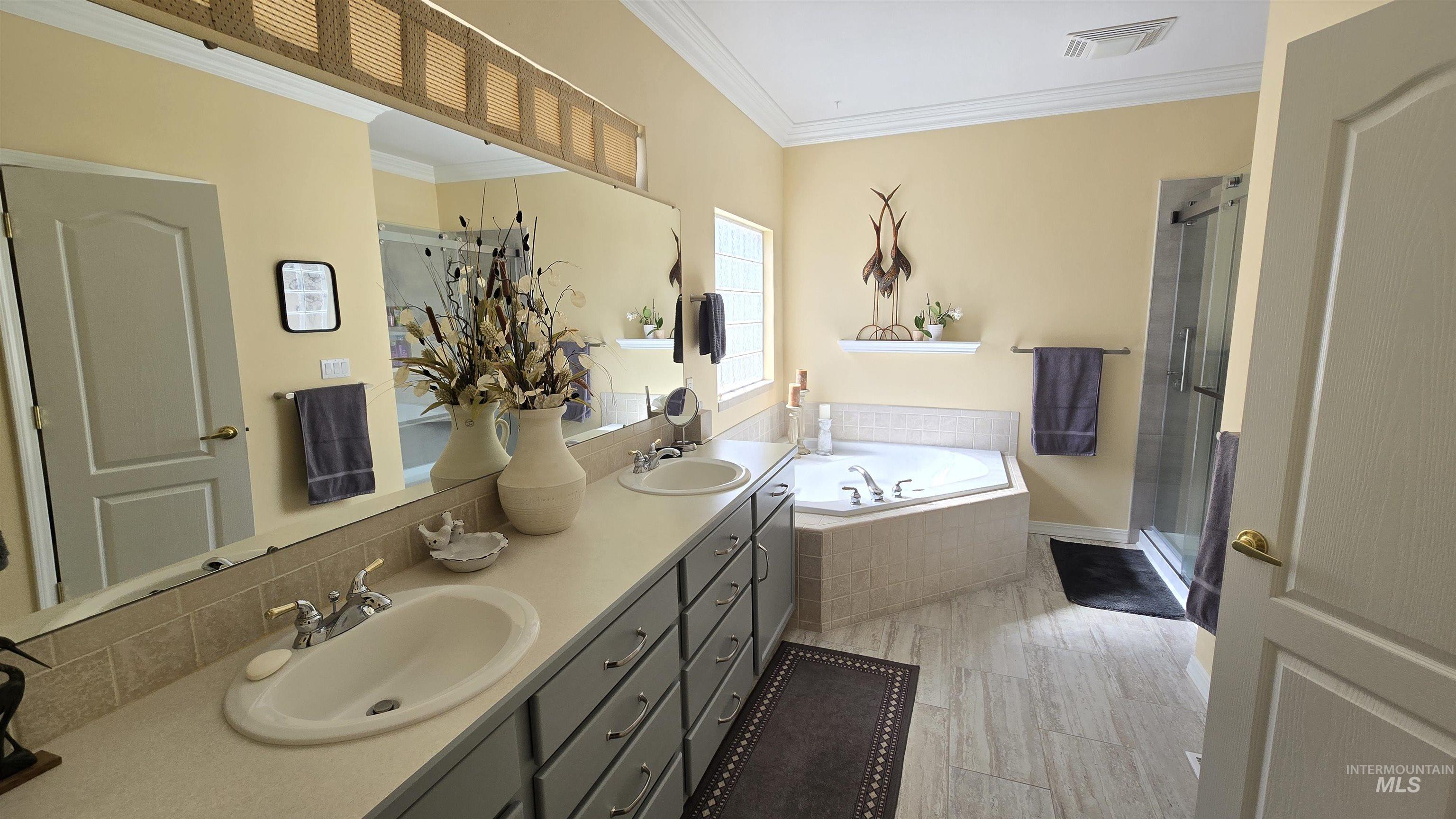 2898 North Silverleaf Way Meridian, ID 83646 - Photo 11 of 26 Bathroom featuring ornamental molding, double vanity, a bath, and a shower stall