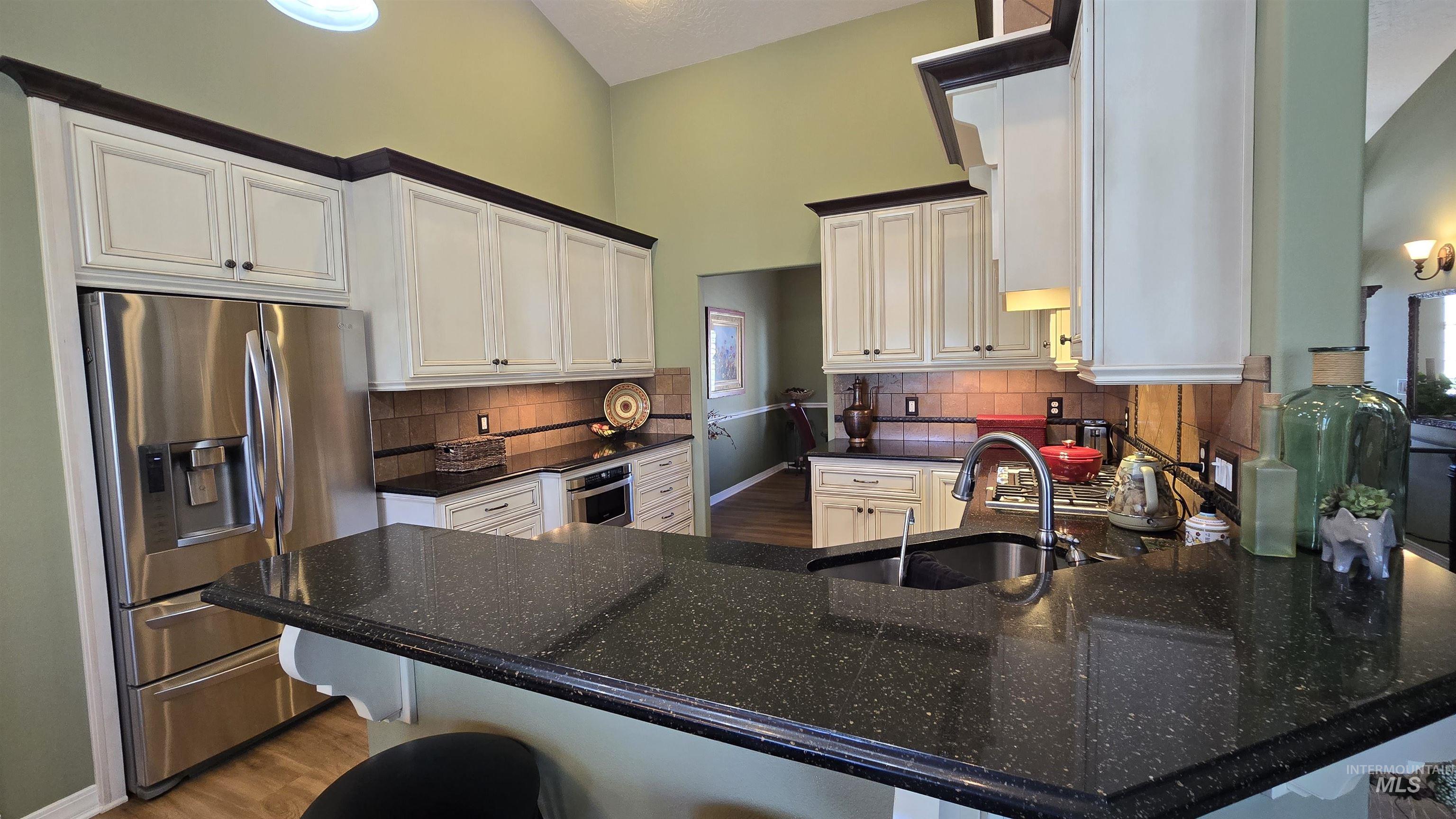 2898 North Silverleaf Way Meridian, ID 83646 - Photo 14 of 26 Kitchen with stainless steel appliances, light wood finished floors, a peninsula, white cabinets, and dark stone counters
