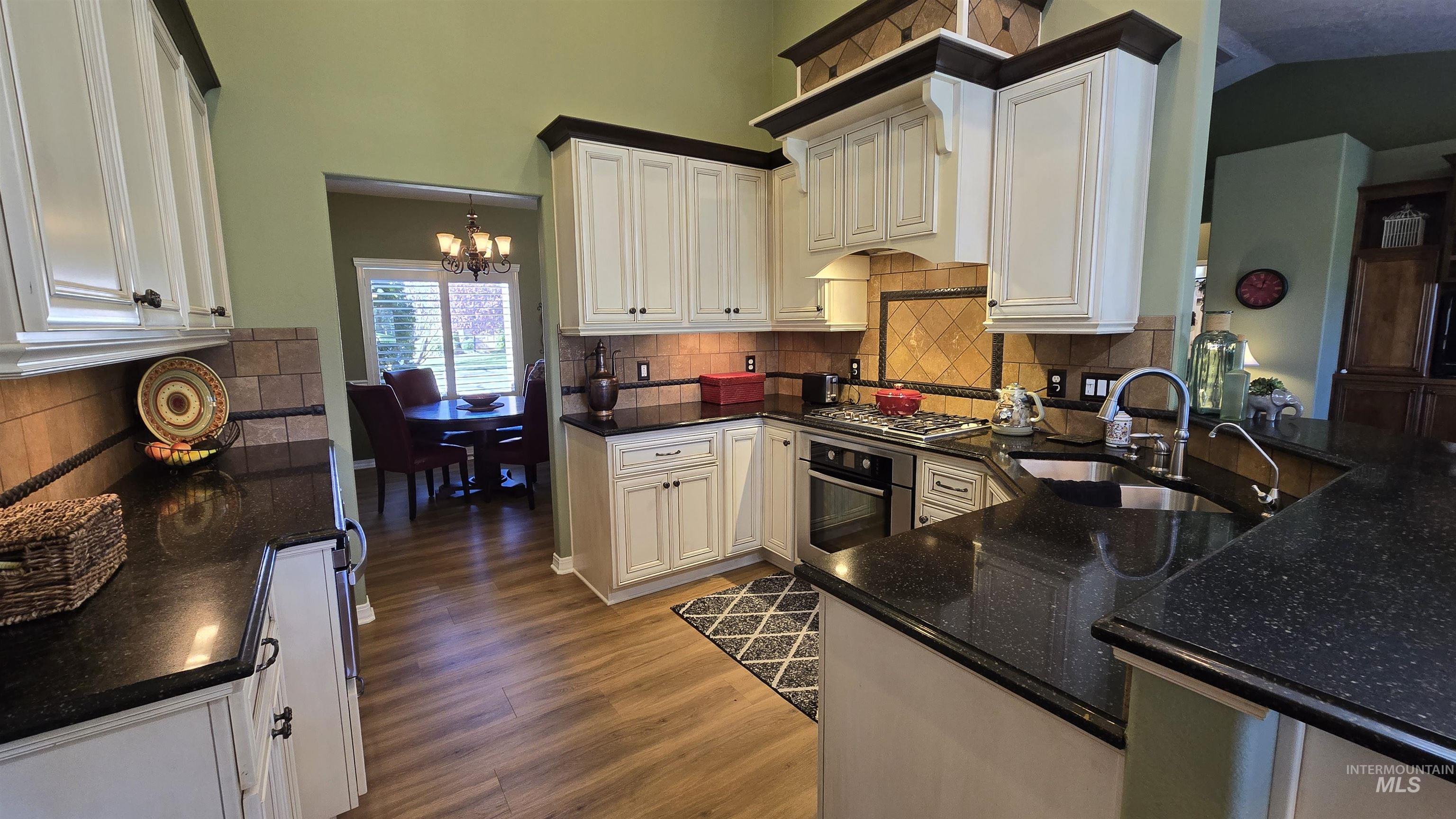 2898 North Silverleaf Way Meridian, ID 83646 - Photo 16 of 26 Kitchen with stainless steel appliances, hanging lights, dark stone countertops, white cabinets, and decorative backsplash