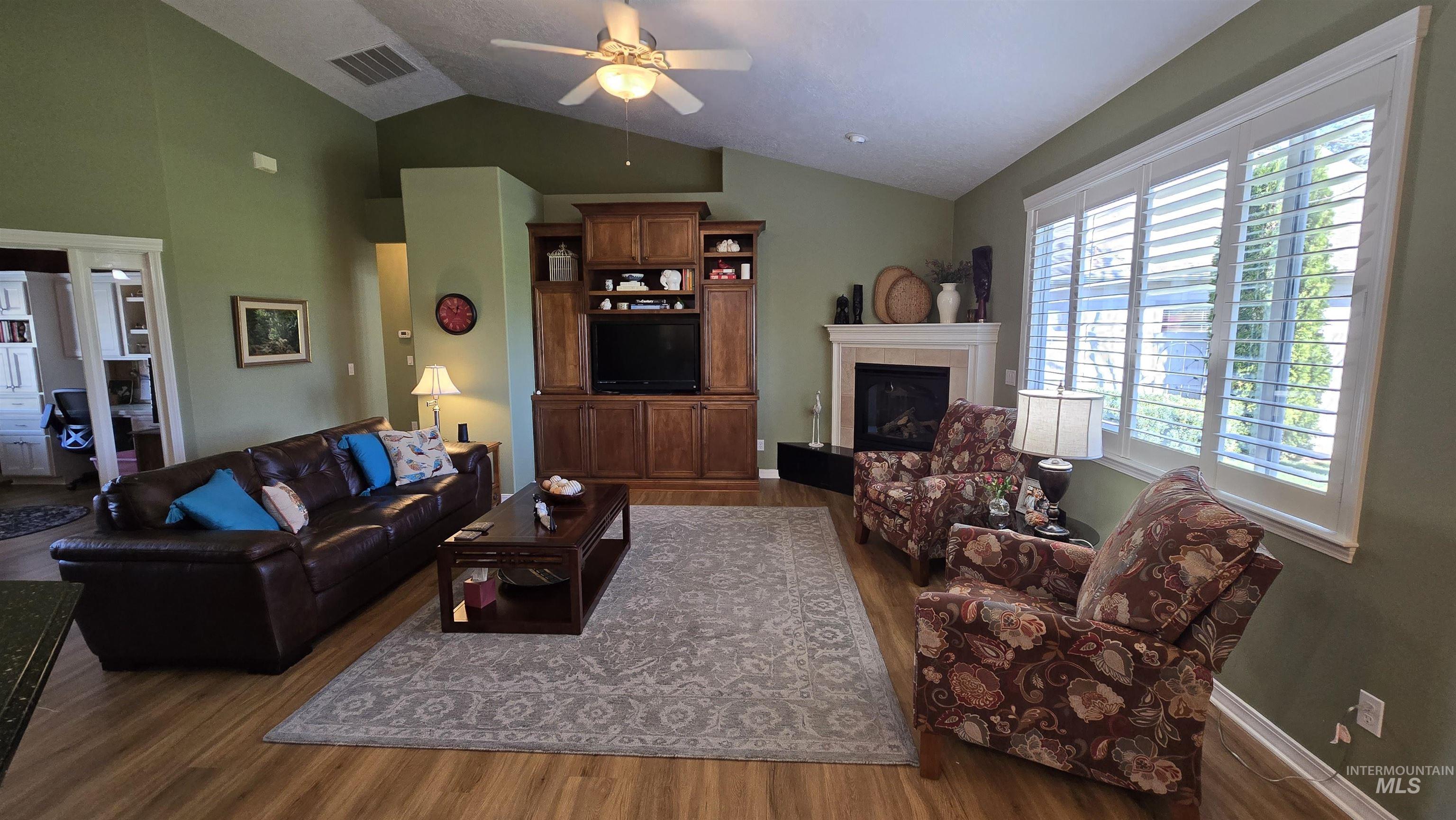 2898 North Silverleaf Way Meridian, ID 83646 - Photo 23 of 26 Living area featuring vaulted ceiling, ceiling fan, dark wood-style floors, and a fireplace