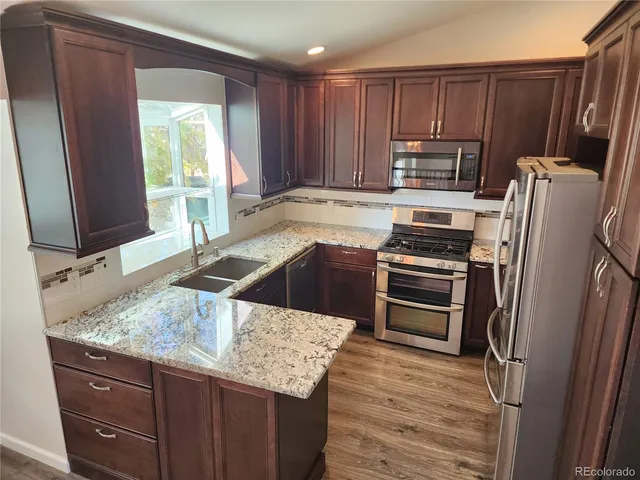 a kitchen with stainless steel appliances granite countertop a sink stove and refrigerator