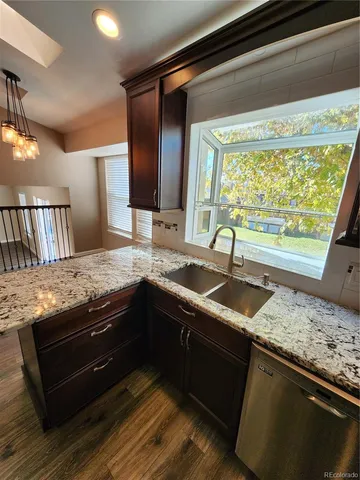 a view of kitchen with granite countertop sink and cabinets