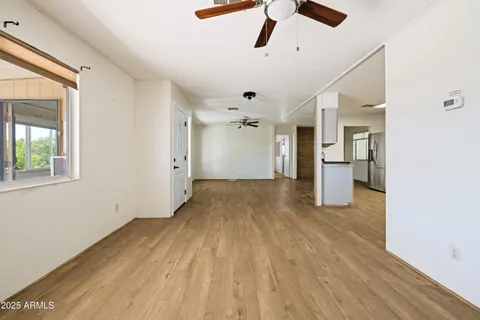 an empty room with wooden floor ceiling fan and windows