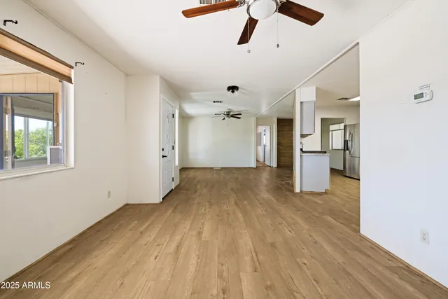 an empty room with wooden floor ceiling fan and windows