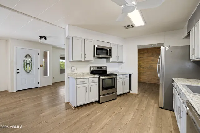 a kitchen with stainless steel appliances granite countertop a sink stove microwave and refrigerator