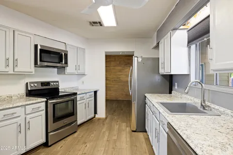 a kitchen with granite countertop white cabinets white appliances and sink