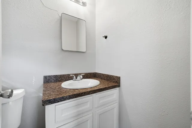 a bathroom with a granite countertop sink a toilet and shower