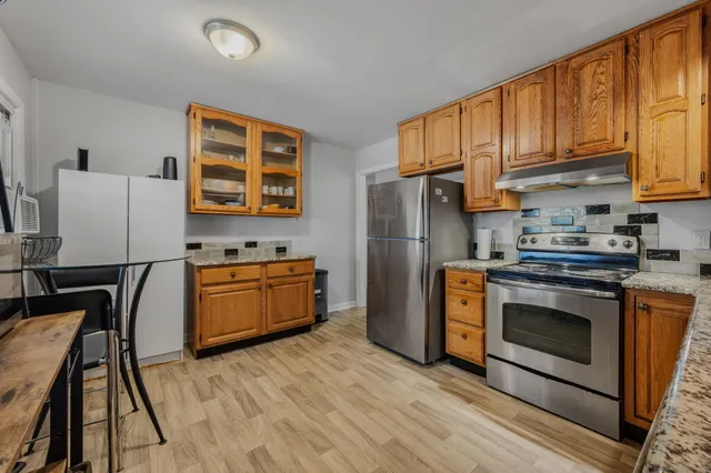 a kitchen with stainless steel appliances granite countertop a refrigerator a stove top oven a sink and dishwasher with wooden floor