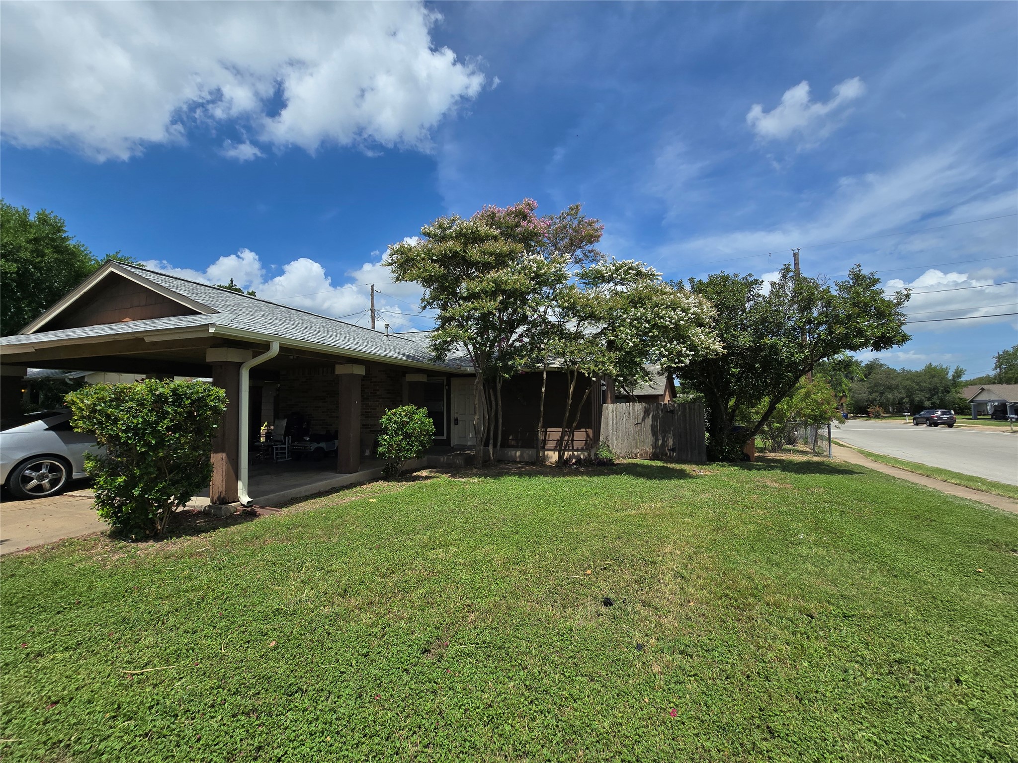 6206 Buffalo Pass, Unit A Austin, TX 78745 - Photo 2 of 24 A welcoming front exterior offers a carport and lush green lawn, bordered by mature trees.