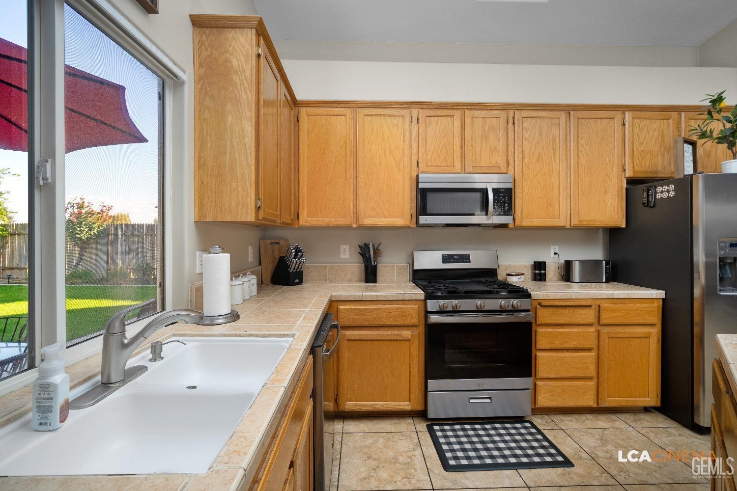 Undisclosed Address Bakersfield, CA 93311 - Photo 7 of 26 a kitchen with stainless steel appliances a stove a sink and a microwave