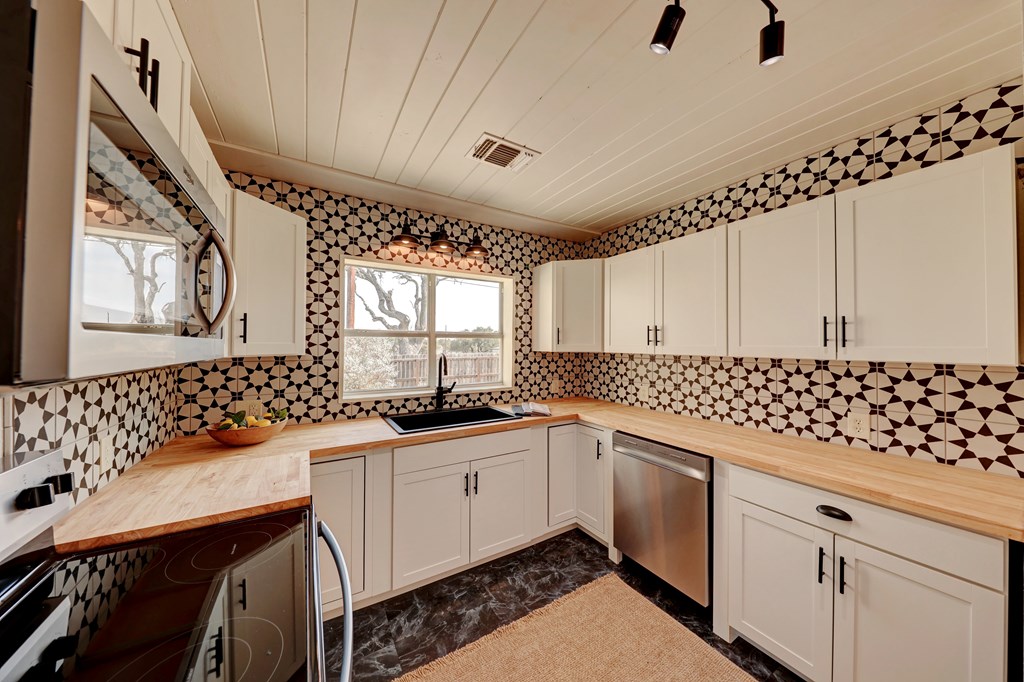 102 Myrtle Avenue Harper, TX 78631 - Photo 14 of 49 a kitchen with granite countertop a sink a stove cabinets and counter space