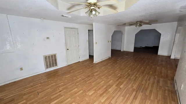 a view of a hallway with a ceiling fan and wooden floor