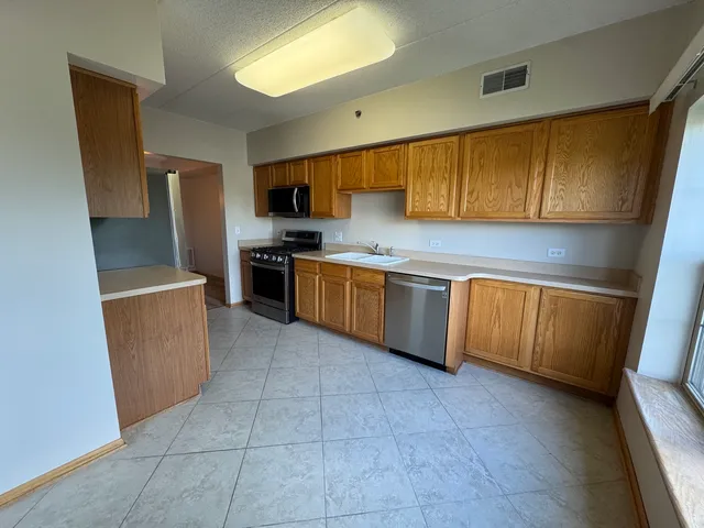 a kitchen with a sink a counter top space cabinets and stainless steel appliances