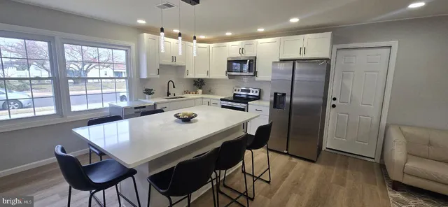 a kitchen with refrigerator and wooden floor