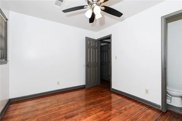 an empty room with wooden floor ceiling fan and window