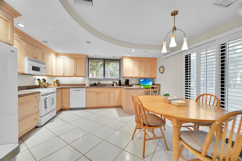 1171 North Ocean Boulevard, Unit 1A N Delray Beach, FL 33483 - Photo 8 of 41 a kitchen with white cabinets stainless steel appliances and dining table