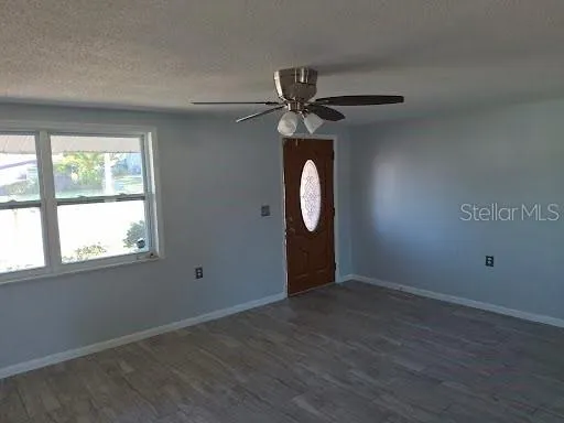 an empty room with wooden floor mirror and windows