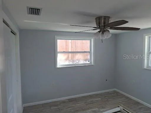 an empty room with a window and a ceiling fan