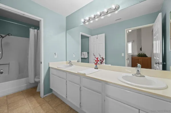a bathroom with double vanity and a mirror