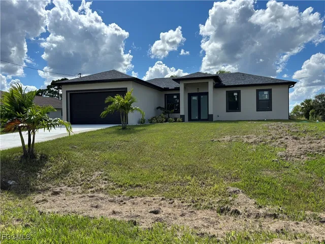 a view of a house with a yard and a large tree
