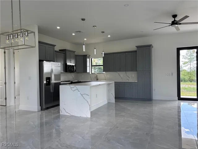 a large kitchen with stainless steel appliances kitchen island granite countertop a refrigerator and a sink