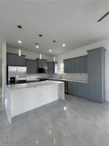 a large white kitchen with stainless steel appliances kitchen island a sink a stove and a refrigerator