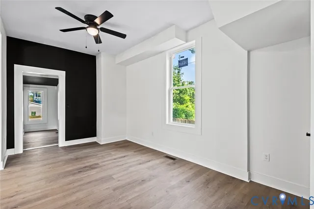an empty room with wooden floor closet and windows