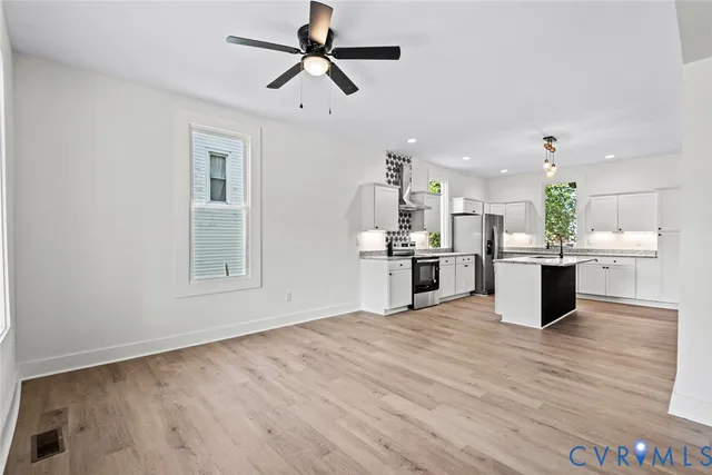 a view of kitchen with kitchen island wooden floor and stainless steel appliances
