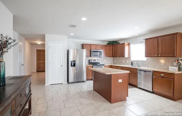 a large kitchen with stainless steel appliances granite countertop a stove and a refrigerator