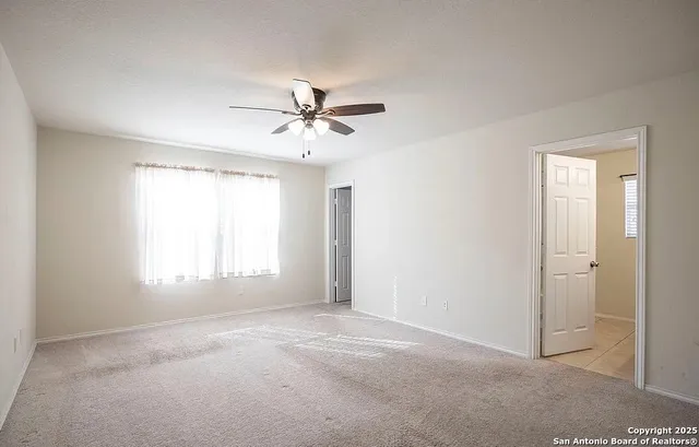 a view of a big room with windows and chandelier fan