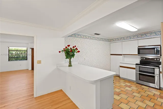 a kitchen with stainless steel appliances kitchen island granite countertop a refrigerator a stove and a wooden floors