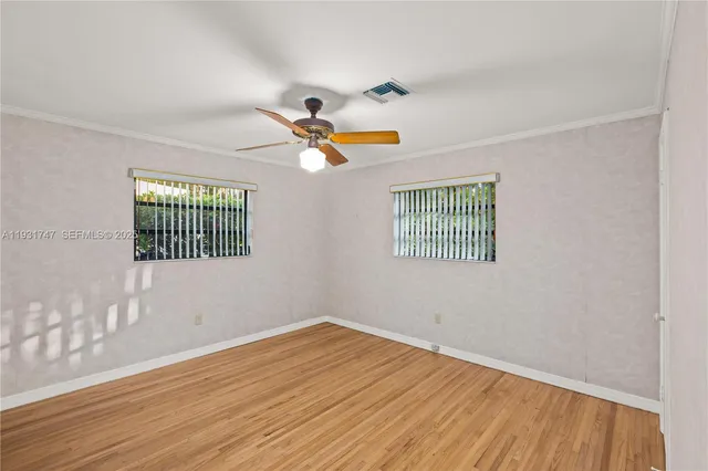 a view of an empty room with window and wooden floor