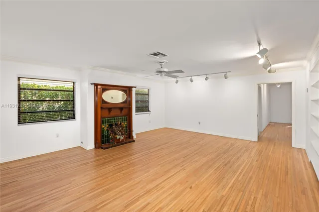 a view of an empty room with window and wooden floor