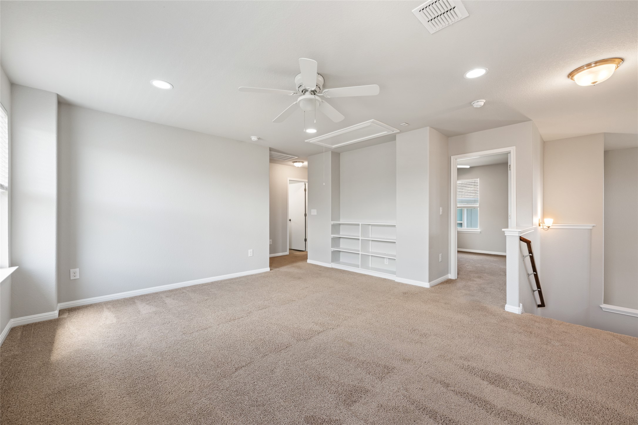 124 Guemal Road Buda, TX 78610 - Photo 23 of 40 A spacious secondary living area features built-in shelving, carpet flooring, and abundant recessed lighting.